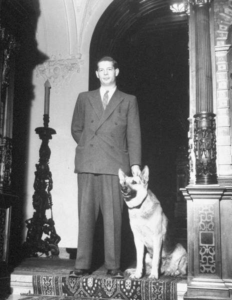 King Michael of Rumania standing in main building of his Sinaia palace with his dog.