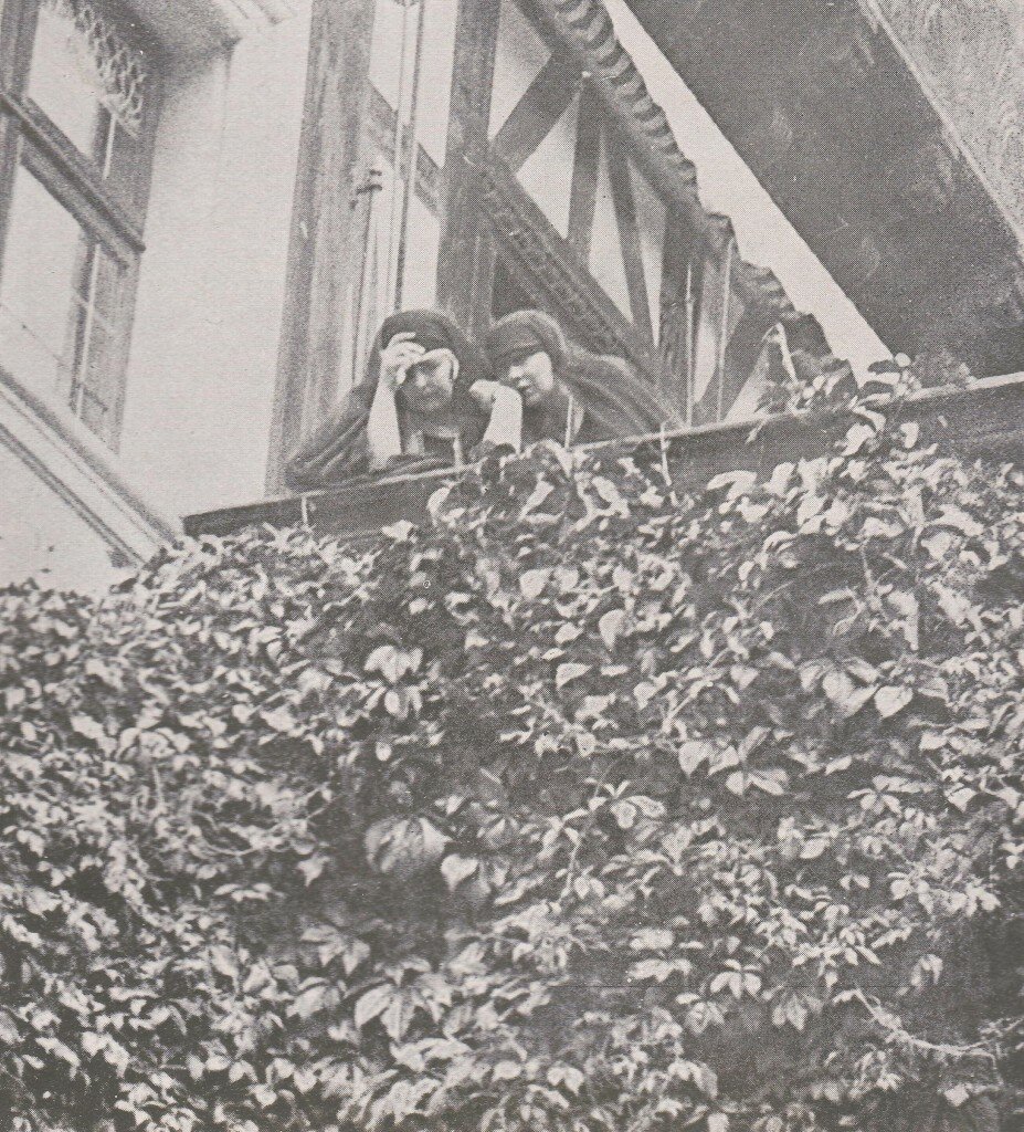 Thier Majestyes Queen Marie and Queen Marioara of Jugoslavia looking down from the Peles Castle and weeping , whilst the funeral procession is leaving the courtyard of the castle