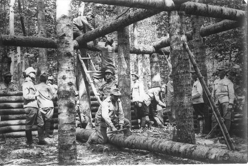 Construction of a wooden shelter in the forest, ladders, axes and soldiers at work