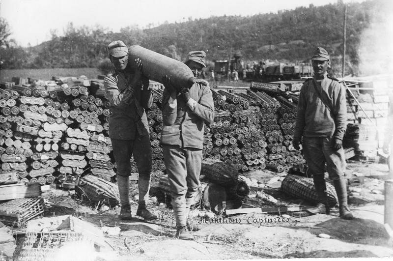 Trophies taken from the enemy. a lot of ammunition, two soldiers carrying a large shell on their shoulders